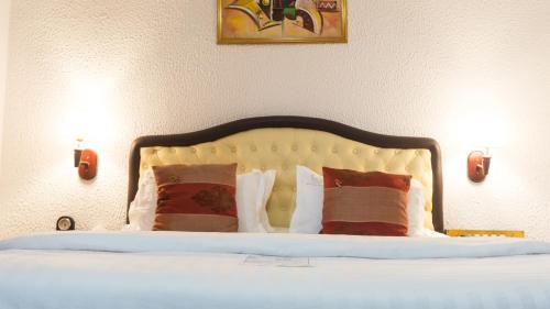 a bedroom with a bed with two lights on the wall at Millenium Popo Beach Hotel in Grand-Popo