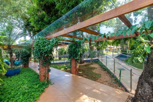 a garden with a wooden pergola and trees at Cataratas Park Hotel e Eventos in Foz do Iguaçu