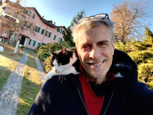 a man holding a black and white cat on his shoulder at Villa Le Vignole in Ameno