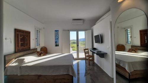 1 Schlafzimmer mit 2 Betten, einem Schreibtisch und einem Fenster in der Unterkunft Arion suites Mykonos in Mykonos Stadt