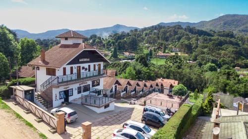 uma vista aérea de um edifício com carros estacionados num parque de estacionamento em Pousada Cantinho De Monte Verde em Monte Verde