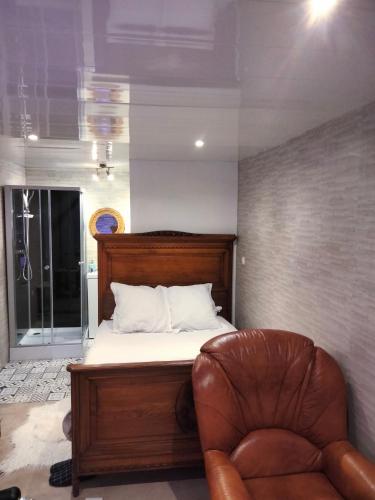 - une chambre avec un lit et un fauteuil en cuir dans l'établissement Chambre meublée indépendante, jacuzzi dans la chambre à 60110 Amblainville près de Paris, à Amblainville