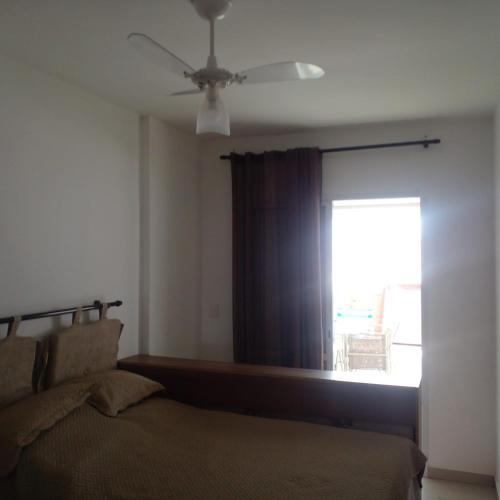 a bedroom with a bed with a ceiling fan and a window at Apartamento alto padrão vista mar in Praia Grande