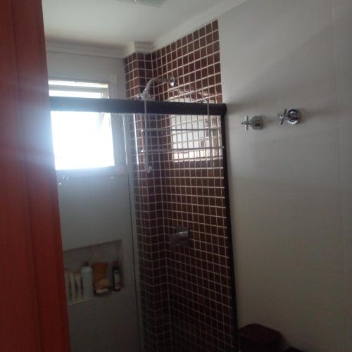 a bathroom with a shower with a tile wall at Apartamento alto padrão vista mar in Praia Grande