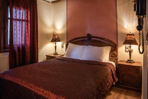 a bedroom with a bed with two lamps on tables at Archontiko Mesohori Meteora in Kalabaka