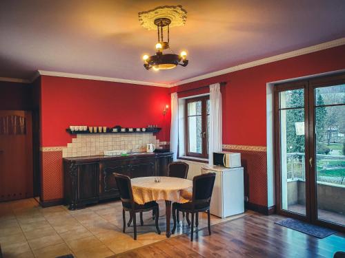 a kitchen with red walls and a table and chairs at Apartamenty nad Wisłą Renesans in Wisła