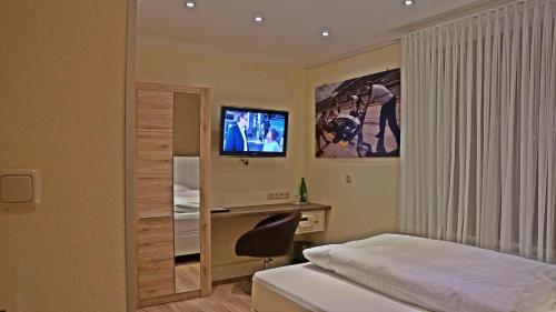 a bedroom with a bed and a desk and a television at Hotel Eifelstube in Rodder