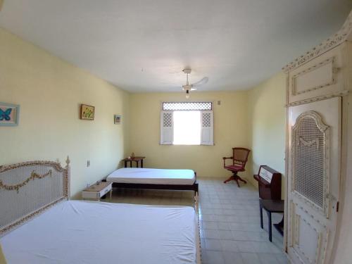 a bedroom with a bed and a window and a chair at Refúgio da Mangueira in Barra dos Coqueiros