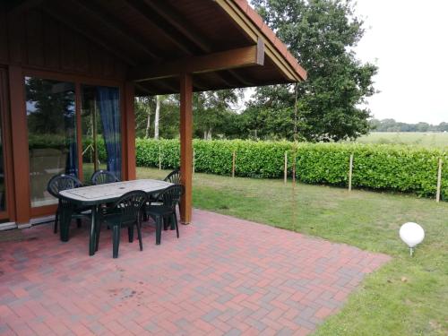 un patio con tavolo e sedie su un patio in mattoni di Haus Vier Pfoten - Hundefreundliches Ferienhaus an der Nordsee a Schweiburg
