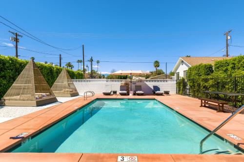 a swimming pool with a wooden deck next to a house at Saint Boniface Hotel in Indio