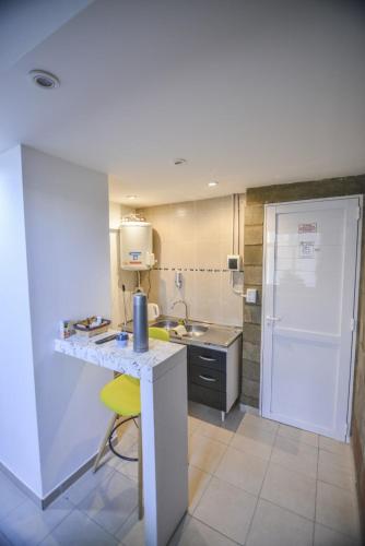 a kitchen with a white counter and a yellow chair at LAS MARAS SUITES in Viedma