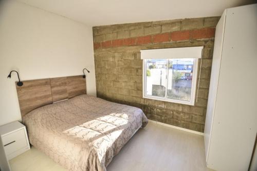 a bedroom with a bed and a brick wall at LAS MARAS SUITES in Viedma