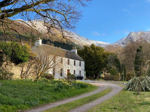 a stone house on a road next to a mountain at Ballachulish House Apartment in Ballachulish