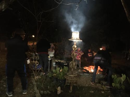 a group of people standing around a fire at night at Quo Vadis Farm in Māngwa
