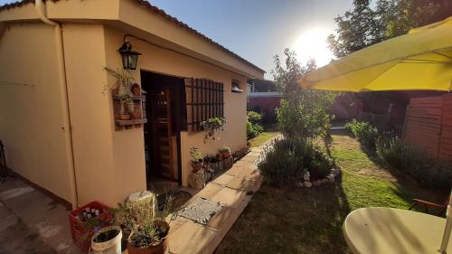 a house with a garden with potted plants and an umbrella at La casita del colibri in Córdoba