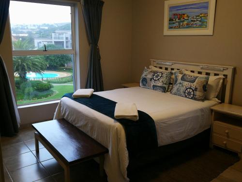 a bedroom with a bed and a large window at 69 Portobelo in Mossel Bay