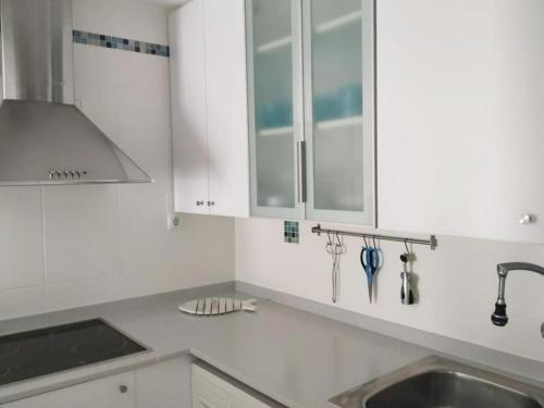 a kitchen with white cabinets and a sink at Little Paradise . Apartment in front of the sea in Comarruga