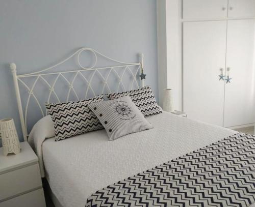 a white bed with black and white sheets and pillows at Little Paradise . Apartment in front of the sea in Comarruga
