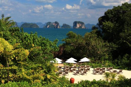 a beach with chairs and umbrellas and the ocean at Six Senses Yao Noi in Ko Yao Noi
