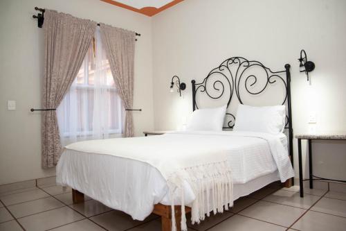 a bedroom with a white bed with a wrought iron headboard at Encanto de la Sierra Hotel in Mascota