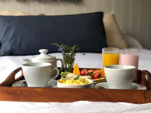 una bandeja de alimentos para el desayuno y bebidas en una cama en Village de las Pampas Apart Hotel Boutique, en Mar de las Pampas