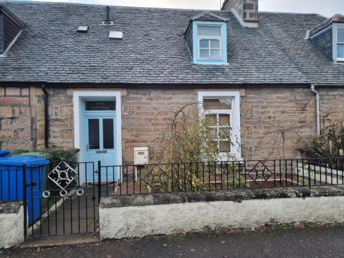 a brick house with a blue door and a fence at Rose Cottage City Centre in Inverness