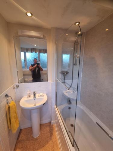 a man taking a picture of a bathroom with a sink and shower at Rose Cottage City Centre in Inverness