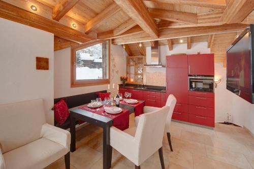 une cuisine avec des placards rouges, une table et des chaises dans l'établissement Chalet Alpoase, à Zermatt