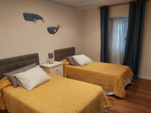 a bedroom with two beds with yellow sheets and a window at Apartamento BRUMA DE LUARCA in Luarca