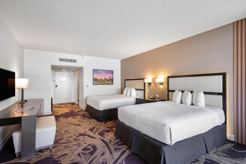 a hotel room with two beds and a flat screen tv at Hotel Zoso in Palm Springs