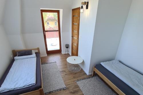 a room with two beds and a door with a table at Mihelyünk in Fonyód