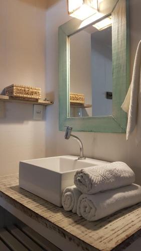 a bathroom with a sink and a mirror and towels at Nordestina Casa de Mar in Icaraí