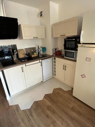  La cuisine est équipée de placards blancs et d'un réfrigérateur. dans l'établissement Joli appartement 2 pièces proche plage, à Fréjus