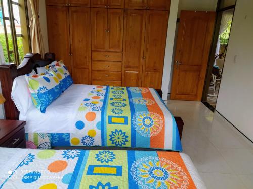 a bedroom with two beds and wooden cabinets at Cabaña Campestre Santa Helena in Choachí