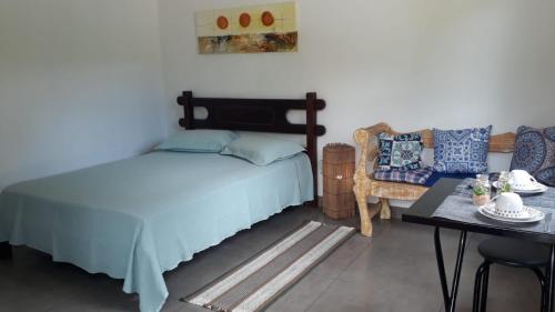ein Schlafzimmer mit einem Bett, einem Tisch und einem Stuhl in der Unterkunft Casa do Ipê - Hospedagem in Lumiar