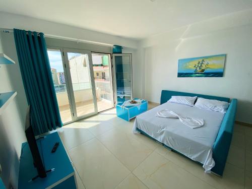a bedroom with a blue bed and a large window at Saranda Terraces Apartment Rentals in Sarandë