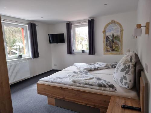 a bed in a bedroom with two windows at Pension "Lug ins Land" in Kurort Rathen