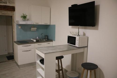 a kitchen with a counter with a microwave on the wall at Studios Kadena Trogir - 18th century stone house in Trogir