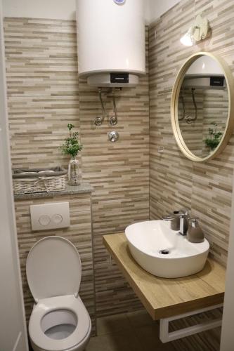 a bathroom with a sink and a toilet and a mirror at Studios Kadena Trogir - 18th century stone house in Trogir