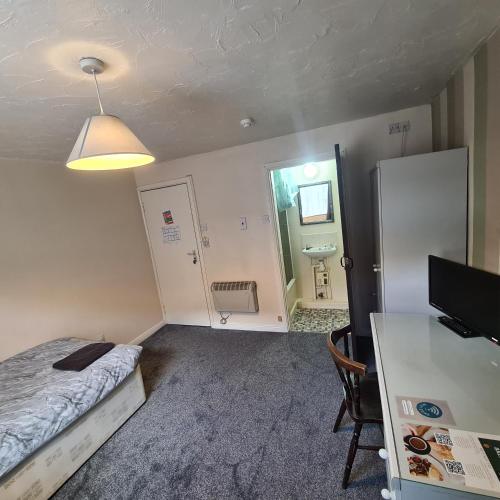 a small room with a bed and a desk and a television at The Coach House in Kegworth