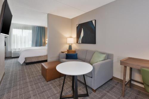 a hotel room with a couch and a table and a bed at Staybridge Suites Pittsburgh Airport by IHG in Pittsburgh