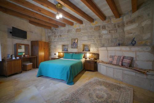 a bedroom with a bed and a stone wall at Salkım Cave House in Göreme