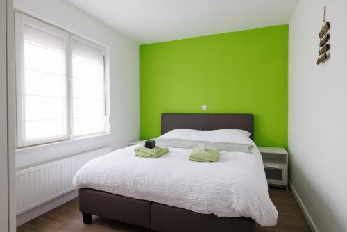 a green bedroom with a bed with two towels on it at Appartement - Vakantiehuis Manou in De Panne
