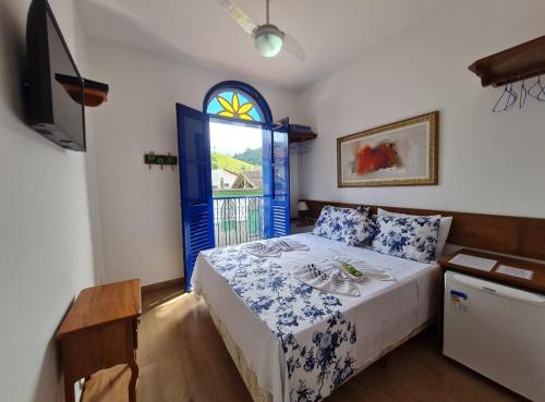 a bedroom with a bed with a blue door and a window at Pousada do Vovô Luiz in Conservatória