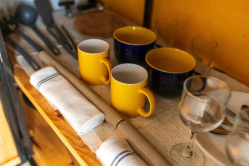 uma mesa com duas chávenas amarelas e um copo de vinho em Amwilla Guesthouse Apartamento Fátima em Mindelo