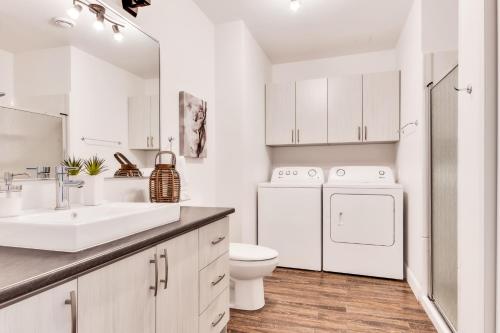 a white bathroom with a sink and a washer and dryer at 25- Chalet à Louer à Stoneham in Stoneham