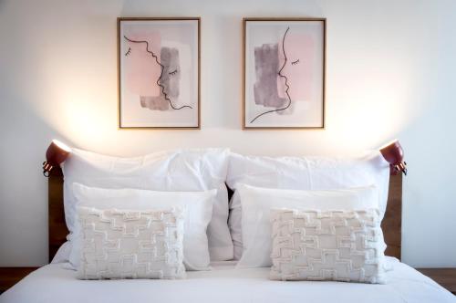a bed with white pillows and two pictures on the wall at bed&breakfast Bohemian in Rovinj