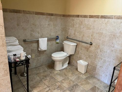 a bathroom with a toilet and a tiled wall at Days Inn & Suites by Wyndham Sutton Flatwoods in Sutton