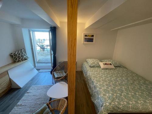 une petite pièce avec un lit et une fenêtre dans l'établissement La Cabine, à Granville