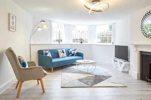 a living room with a blue couch and a tv at Stylish, spacious flat with private parking in Bristol